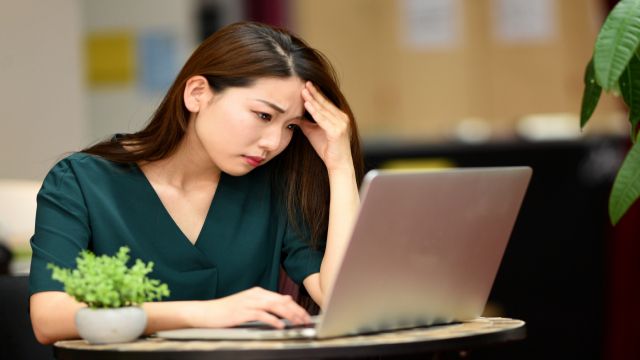 パソコンを見ながらパワハラの悩みで表情が暗い女性